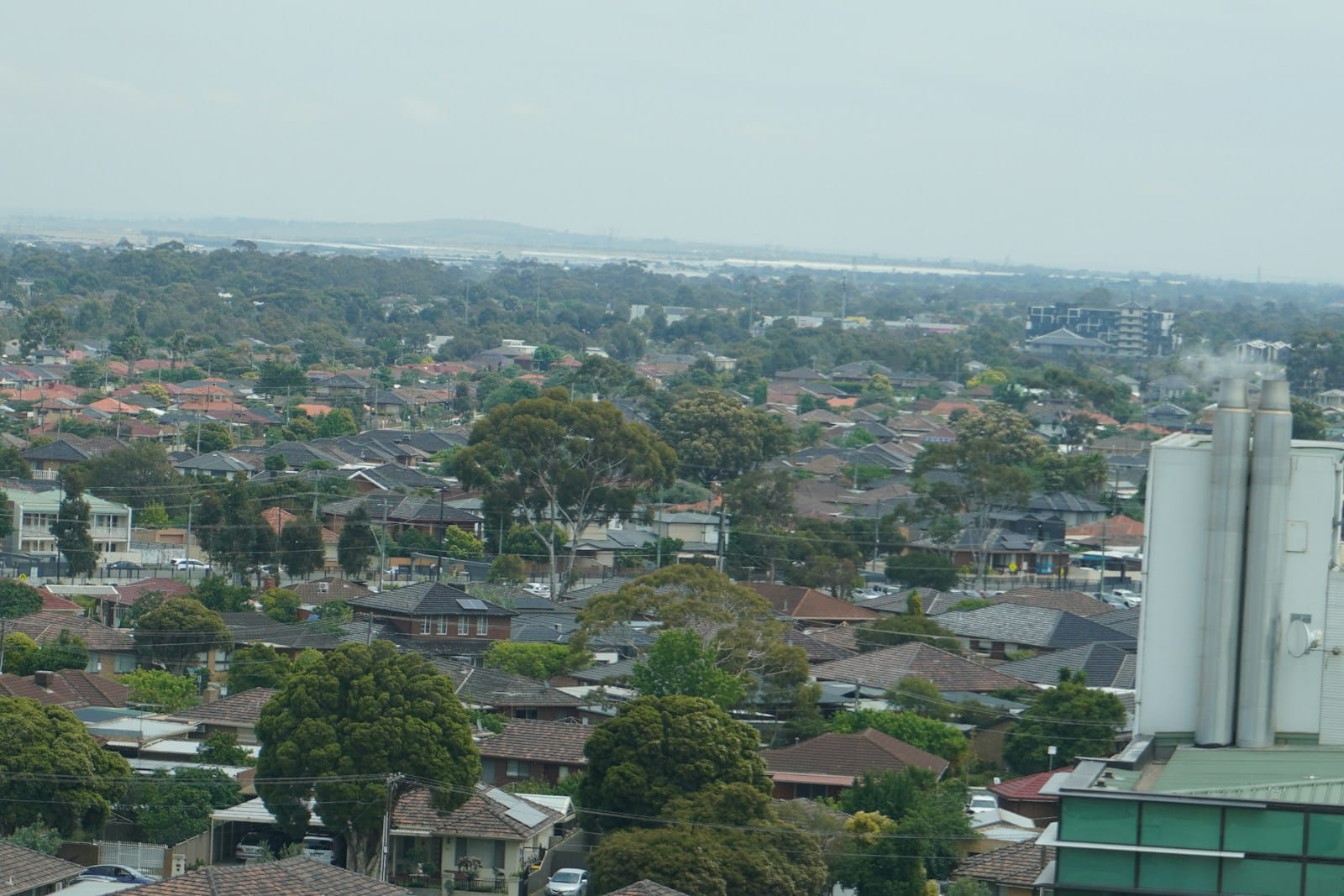 Cityscape with houses and trees under a cloudy sky.