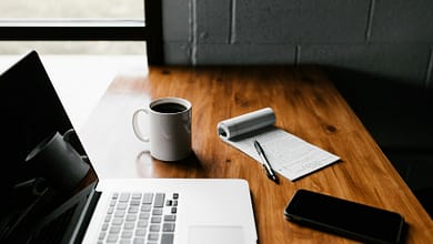 Les outils essentiels pour les blogueurs guinéens. 3 MacBook Pro, white ceramic mug,and black smartphone on table