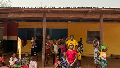 Les risques des prêts informels en Guinée. 11 A group of people standing in front of a yellow building