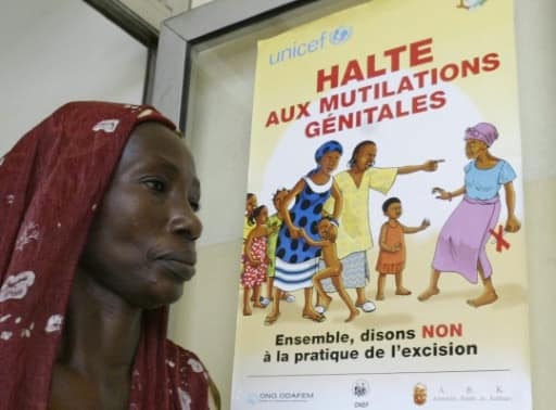Une exciseuse devant un posteur de l'Unicef contre l'excision, à Abidjan, le 17 novembre 2005 | AFP/Archives | KAMBOU SIA